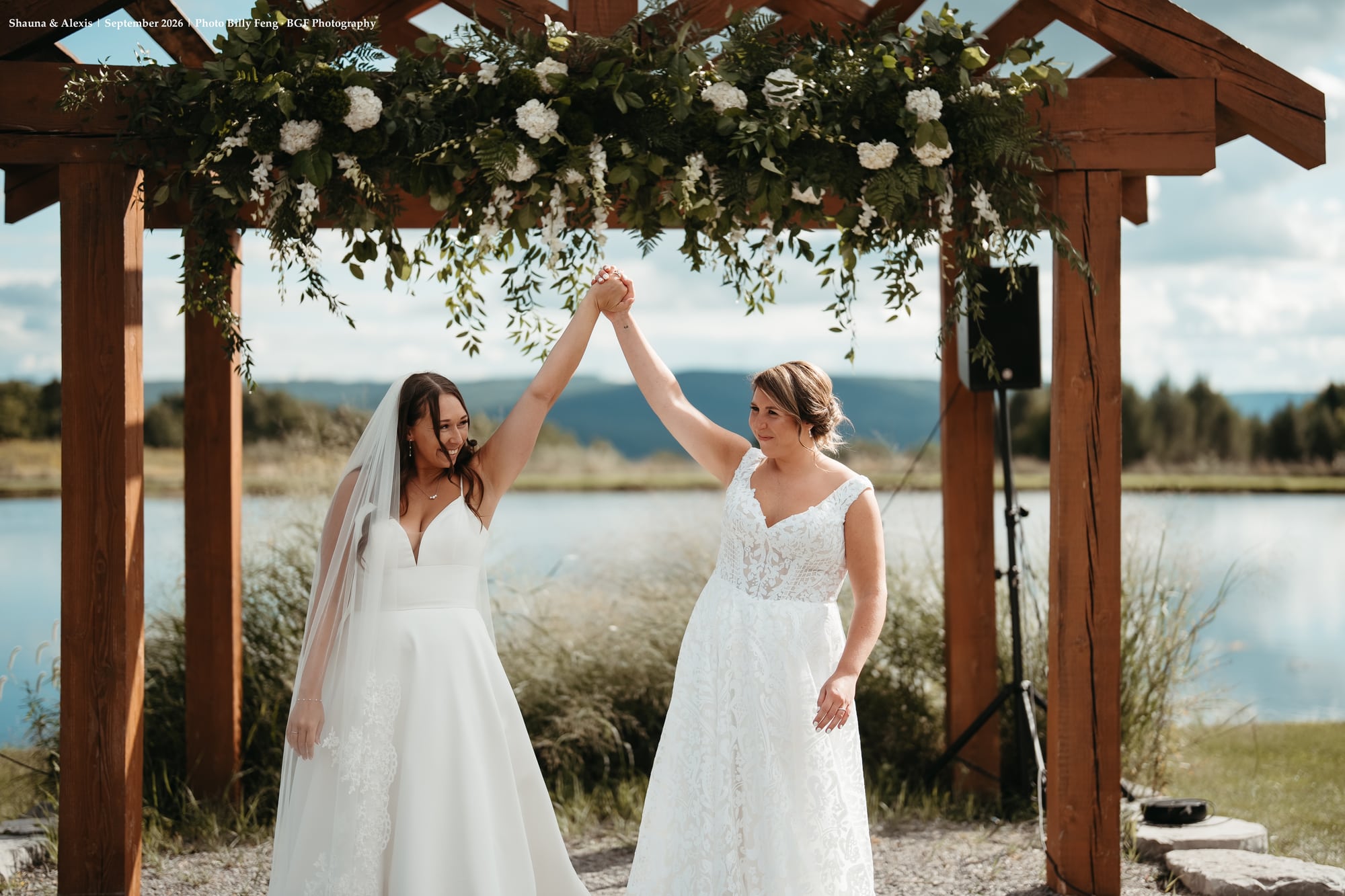 Shauna and Alexis celebrating under lake ceremony arbor