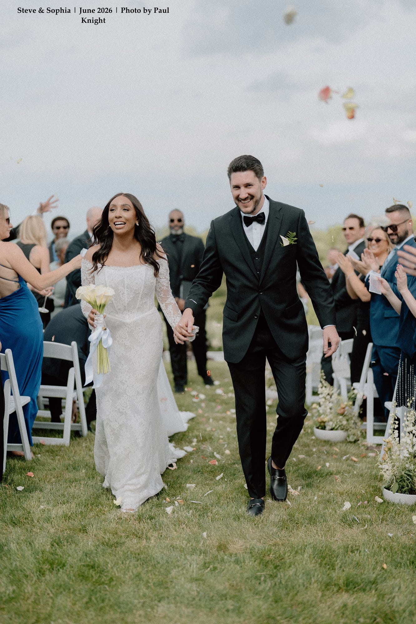 Newlyweds Sophia and Steve smiling as guests applaud down the aisle