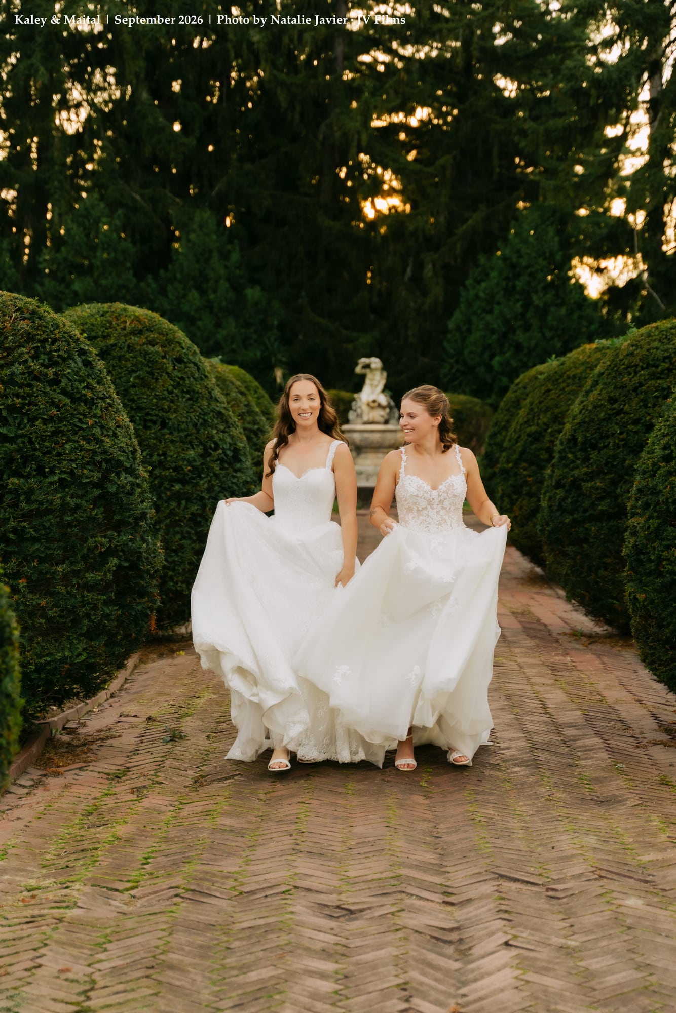 Newlywed brides joyfully walking through historic garden arches at Sonnenberg Gardens
